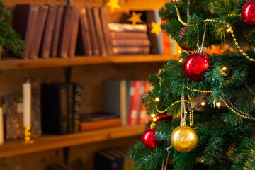 Christmas tree decorated with garlands and balls, against the background of the library bookshelves. New Year or Christmas background. Greeting card.