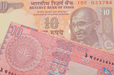 A macro image of a orange ten rupee bill from India paired up with a red ten taka bank note from Bangladesh.  Shot close up in macro.