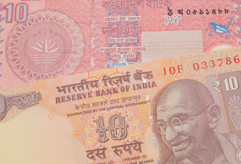 A macro image of a orange ten rupee bill from India paired up with a red ten taka bank note from Bangladesh.  Shot close up in macro.