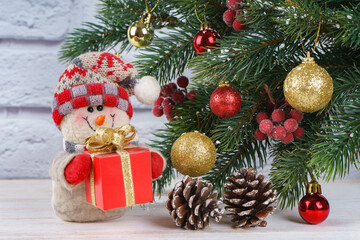 Fototapeta na wymiar New Year snowman with gift on Christmas tree background