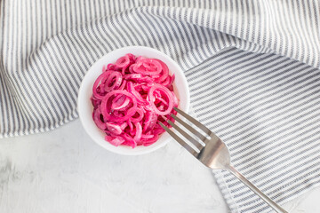 Juicy red onion marinated in lemon juice on a light background.