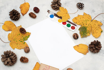 Autumn composition with paints and brushes for drawing, leaves and a gift box.