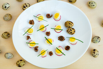 boiled quail eggs with anchovies and chives on a plate