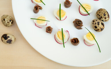 boiled quail eggs with anchovies and chives on a plate