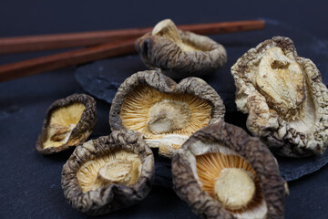 Macro closeup of isolated dried chinese shiitake mushrooms on slate stone background (focus on central mushroom)