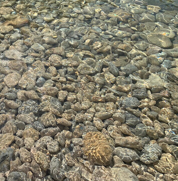 Pebble beach. Crystal clear sea. Ripple on the water. Smooth beautiful stones on the seabed. Relaxation. Mediterranean coast. Transparency.