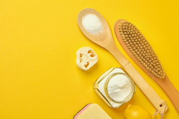Zero waste cleaner concept soda can, wooden brush, lemon, citric acid, sponge and loofah on yellow background, copy space top view
