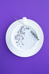 Top view of lavender moon milk in the white cup on the violet surface.  Location vertical.