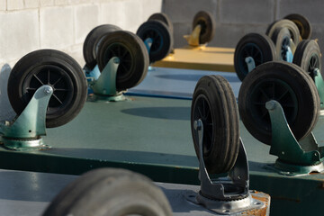 Upside down trash bins with wheels upside down against a gray brick wall.
