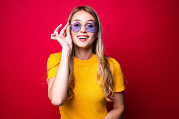 Young pretty blonde woman with sunglasses on red background