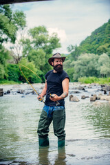 Man fisherman holds a fish. Happy cheerful people. Fishing in river. Angler catching the fish. Bearded man catching fish. Fisherman show fishing technique use rod. Having a good time.