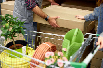 close-up photo of shopping trolley in store full with things for home, customers going to buy something, they hold cardboard box
