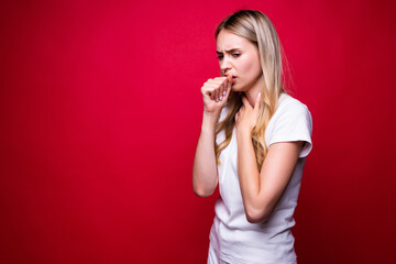 Young beautiful blonde woman over red isolated background feeling unwell and coughing as symptom...