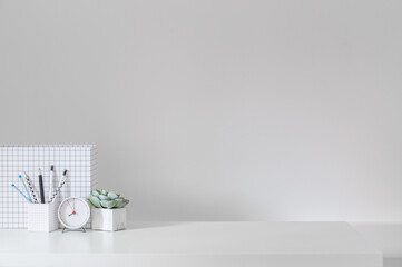 Creative desk with a blank picture frame or poster, desk objects, office supplies, books, and plant on a dark blue background.	