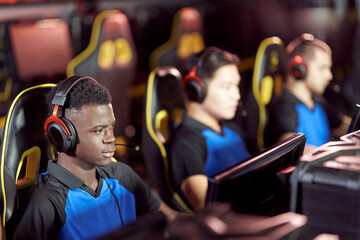 Team of young professional cybersport gamers wearing headphones participating in eSport tournament