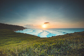 Naklejka na ściany i meble Indonesia ocean sunrise, green cliff beach nobody nature landscape with greenery grass at clear sky in summer, Wild Sumba Island, Asia. Majestic Indonesian National Park on rock shore of Indian Gulf