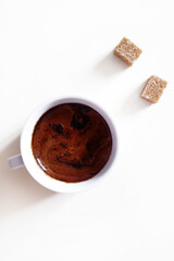 Cup of black espresso coffee with foam and two pieces of bamboo sugar isolated on white background. Vertical shot