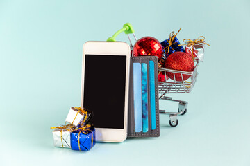 Phone with copy space, shopping cart with gifts, credit cards to buy online. New year and christmas...