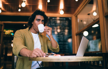 Focused ethnic man drinking coffee in cafe