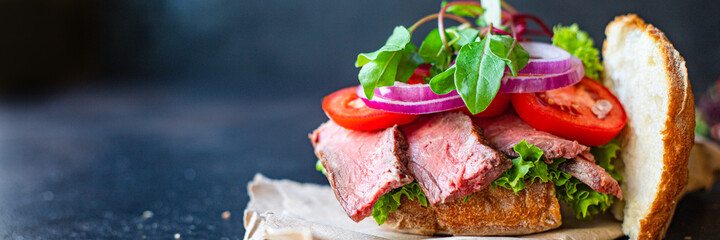 meat sandwich and vegetables burger loaf of bread, tomato, lettuce, medium or rare steak on the table serving size top view copy space for text food background rustic