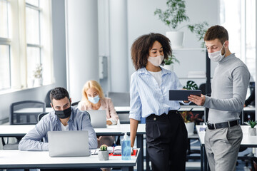 Discussion of colleagues about mistakes in work. Guy and african american woman in protective masks...