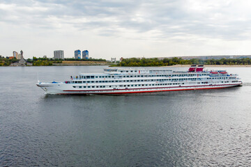 Motor ship. A large cruise ship with tourists on board runs along the Volga downstream towards...