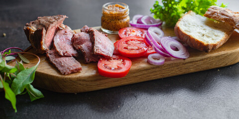 meat sandwich and vegetables burger loaf of bread, tomato, lettuce, medium or rare steak on the table serving size top view copy space for text food background rustic
