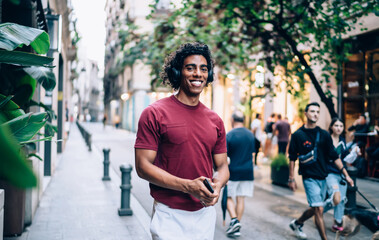 Cheerful man in headphones walking along street