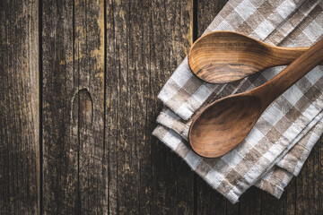 Two wooden spoons on checkered napkin on old wooden table.