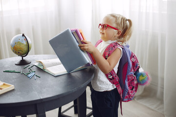 Child study at home . Girl sitting on a table. Kid in a class.
