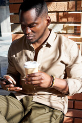 young african man with smartphone in cafe, handsome guy in casual stylish wear sit alone using mobile phone, chatting
