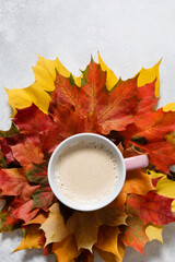 Autumn mood composition. Cup of coffee with maple leaves on white background. Flat lay, top view, copy space.