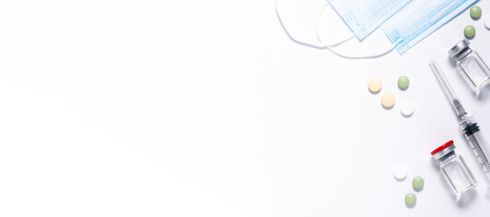 Long wide medical banner with vials with vaccine, syringe, protective masks and tablets on white background. Pandemic prevention concept.