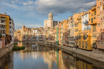 Fototapeta na wymiar Walking Girona - Spain touristic town. Colorful yellow and orange houses and famous house Casa Maso reflected in water river Onyar, in Girona, Catalonia, Spain.