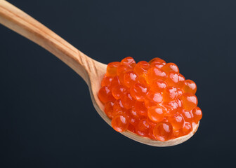Red Caviar on a wooden spoon. Salmon Fish salted caviar. Raw seafood. Delicacy food. Dark background.