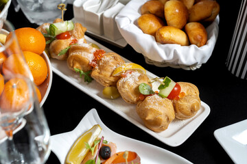 Beautifully decorated catering banquet table with profiteroles, salads and cold snacks. Variety of tasty delicious snacks on the table.