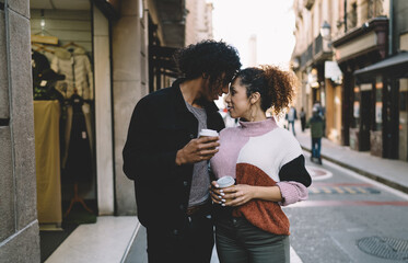 Young couple with takeaway coffee showing affection on street
