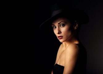 Fototapeta na wymiar Beautiful glamour brunette woman with red lipstick in fashion hat on black background with empty copy space. Closeup portrait. Art.Expression.