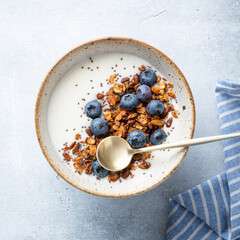 Breakfast, granola with yogurt, blueberries and chia seeds on a light blue background, top view