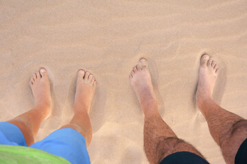 Pies de padre y hijo en la arena de playa 