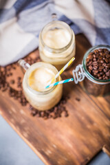 Iced coffee with milk in vintage jar on old wooden table
