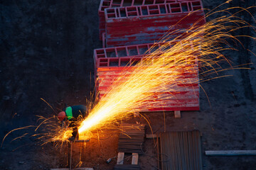 Industrial worker sawing metal with many sharp sparks