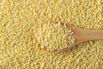 Couscous in wooden spoon background and texture, top view