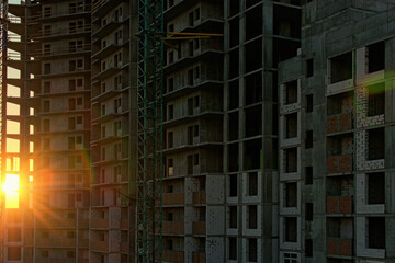 Obraz premium Sun shine through the concrete construction of new multi-storey building. Autumn sunrise in the construction site. Abstract glitter light effect star beam sun. Kyiv, Ukraine
