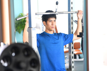 ジムでラットプルダウンをする若い男性