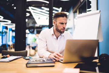 Puzzled male entrepreneur watching video webinar feeling puzzled on received financial information, Caucasian businessman using office internet connection for working with web documents on laptop