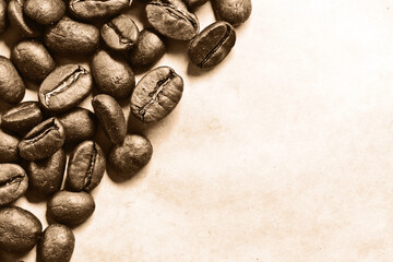 Coffee seeds on vintage paper background. Coffee beans texture. Warm color brown roasted grain. Brown sepia colors photography. Empty copy space rustic parchment paper.