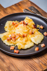 Dumplings with meat, onions and bacon on black plate. Traditional Polish dumplings