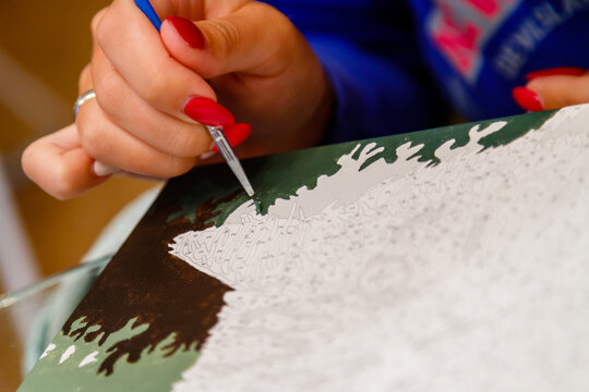Picture by numbers. Drawing on canvas. Woman's hand with brush. Selective focus. Close up.