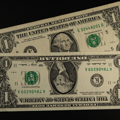 Two paper one dollar bills, new and old.